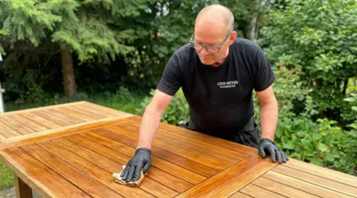 Malermester Leon Meyer behandler teaktræshavebord med olie og handsker