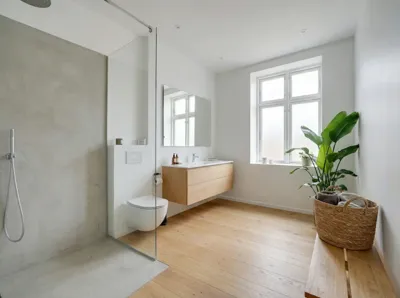 Lyst badeværelse med betonvæg, trægulv og hvide vægge