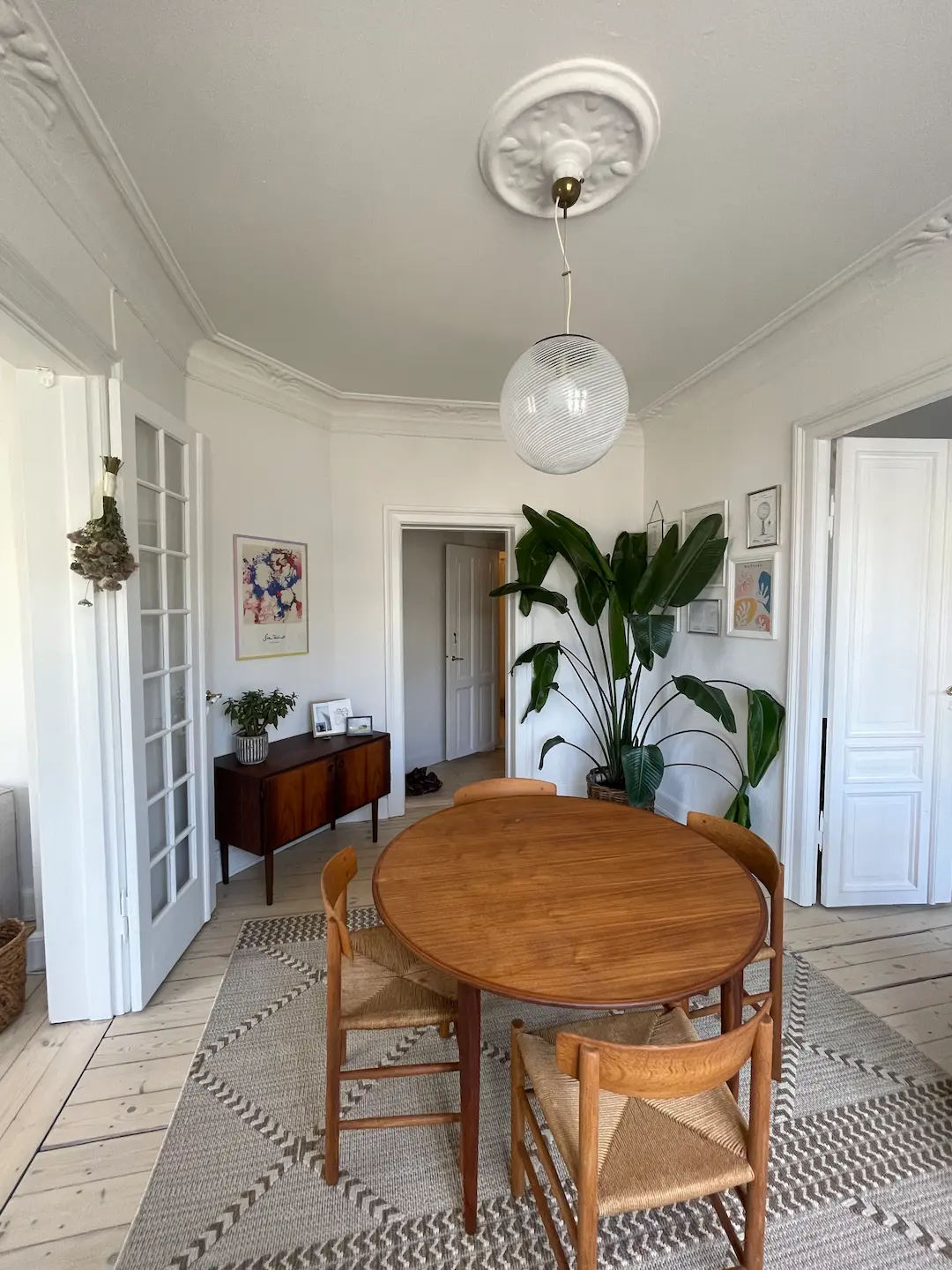 Lyst og velvedligeholdt lejlighedsstue med hvide vægger, stukloft og klassiske fyldingsdøre i dansk etageejendom